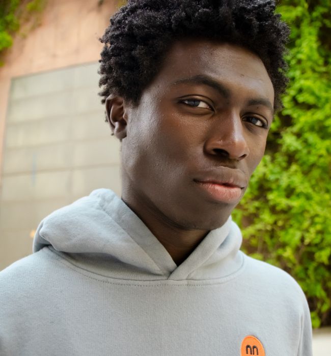 Model wearing barcelona hoodie in grey showing pamuuc embroidered isotope logo on the front.