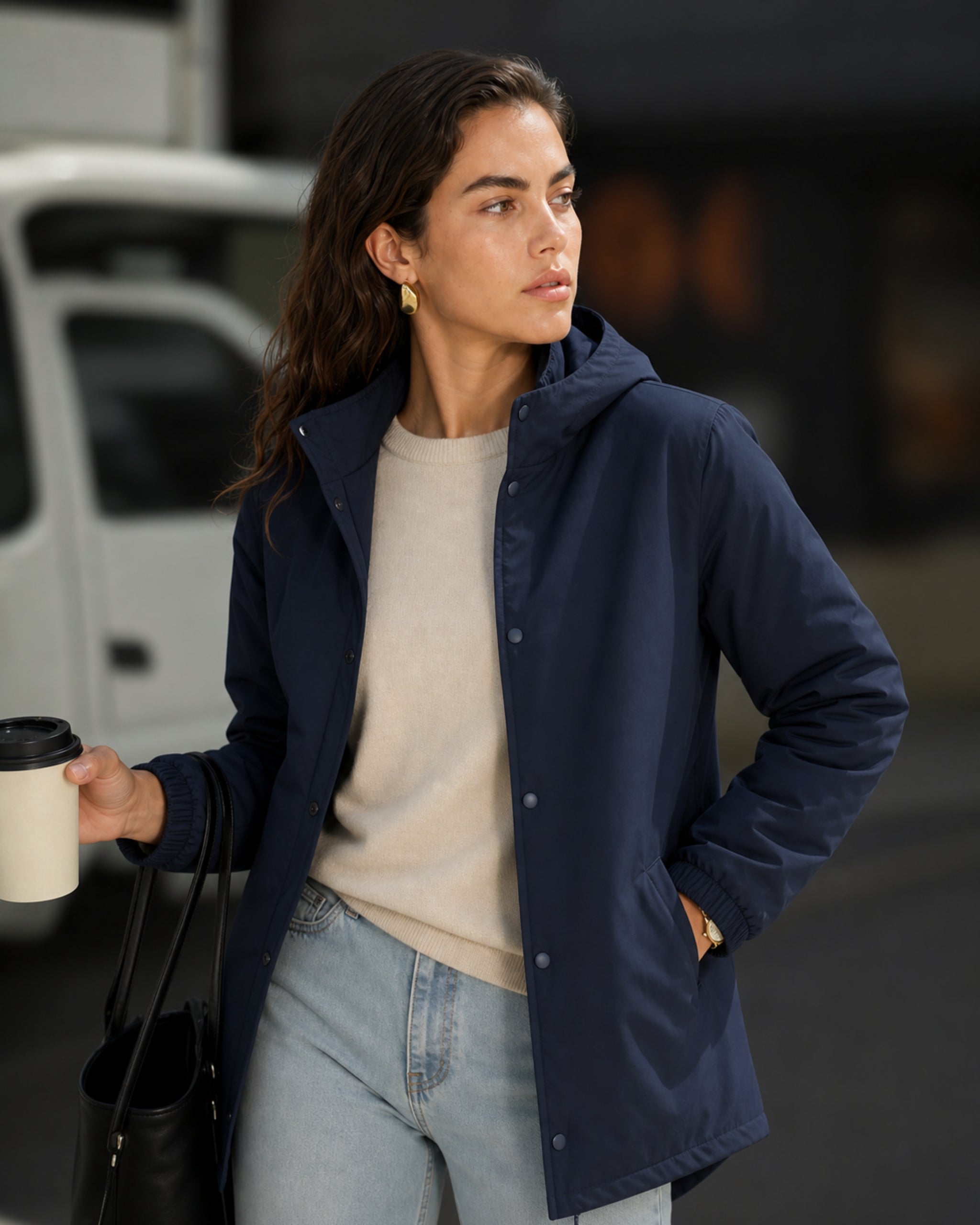 Vrouw in parka in marineblauw houdt vast coffee kopje op straat